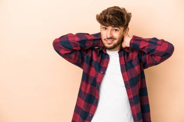 Young arab man isolated on beige background touching back of head, thinking and making a choice.