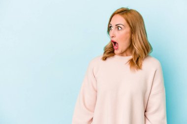 Mavi arka planda izole edilmiş beyaz bir kadın gördüğü bir şey yüzünden şoka uğruyor..