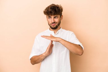 Young arab man isolated on beige background showing a timeout gesture.