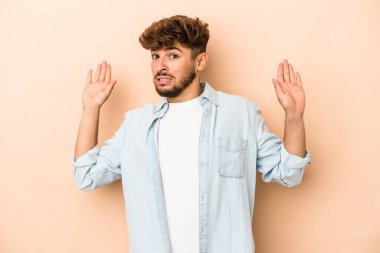 Young arab man isolated on beige background being shocked due to an imminent danger