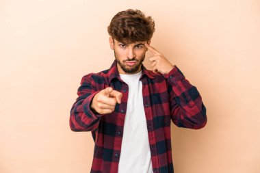 Young arab man isolated on beige background pointing temple with finger, thinking, focused on a task.