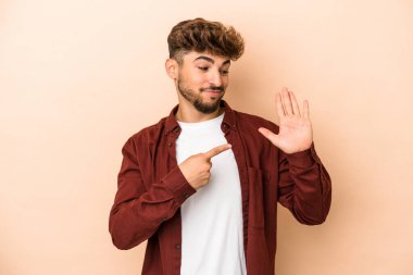 Young arab man isolated on beige background smiling cheerful showing number five with fingers.