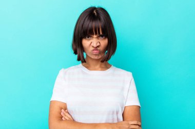 Mavi arka planda soyutlanmış genç melez bir kadın yanakları patlatıyor, yorgun bir ifadesi var. Yüz ifadesi kavramı.