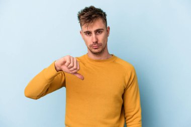 Mavi arka planda izole edilmiş genç beyaz bir adam hoşlanmadığı bir jest yapıyor. Anlaşmazlık konsepti.