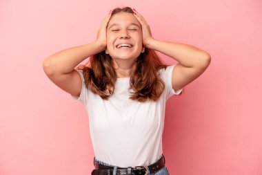 Pembe arka planda izole edilmiş küçük beyaz kız ellerini başının üstünde tutarak neşe içinde gülüyor. Mutluluk kavramı.