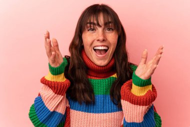 Arjantinli genç bir kadın pembe arka planda izole edilmiş. Hoş bir sürpriz bekliyor, heyecanlı ve el kaldırıyor..