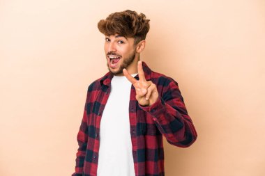 Young arab man isolated on beige background showing number two with fingers.