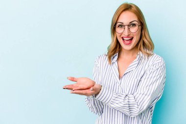 Mavi arka planda izole edilmiş beyaz bir kadın. Elinde palmiye ağacında bir kopya alanı var..