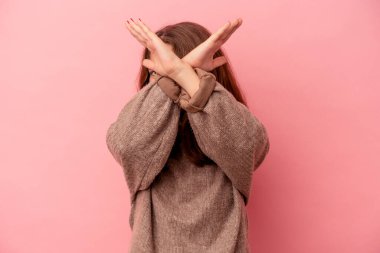 Pembe arka planda izole edilmiş küçük beyaz kız iki kolu çapraz tutuyor, inkar kavramı.