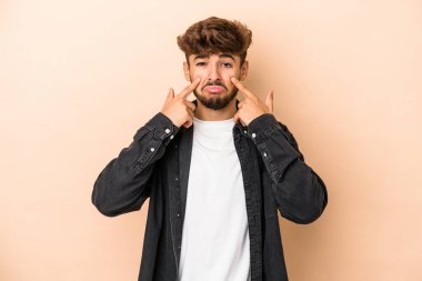 Young arab man isolated on beige background crying, unhappy with something, agony and confusion concept.