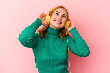 Pembe arka planda izole edilmiş müzik dinleyen beyaz bir kadın.