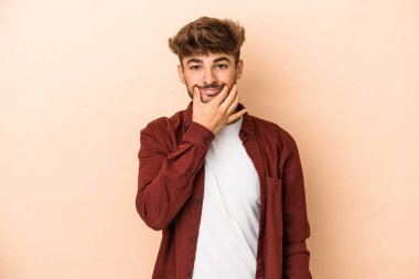 Young arab man isolated on beige background doubting between two options.