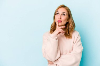 Mavi arka planda soyutlanmış beyaz bir kadın şüpheli ve şüpheci bir ifadeyle yana bakıyor..