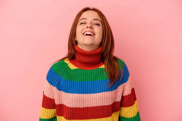 Genç beyaz kadın pembe arka planda izole edilmiş rahat ve mutlu bir şekilde gülüyor, boynunda dişlerini gösteriyor..