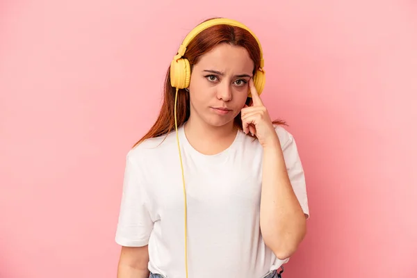 Mujer Caucásica Joven Escuchando Música Aislada Sobre Fondo Rosa Apuntando —  Fotos de Stock