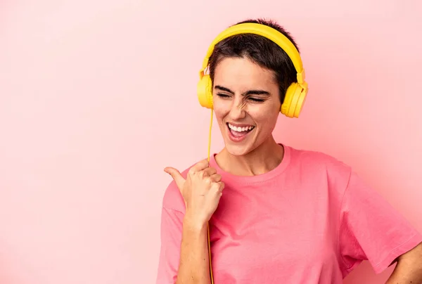 Young Caucasian Woman Listening Music Isolated Pink Background Points Thumb — Φωτογραφία Αρχείου