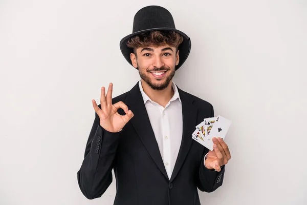 若いですArabウィザード男保持Aマジックカード隔離上の白い背景陽気で自信を持ってショーOkジェスチャー — ストック写真