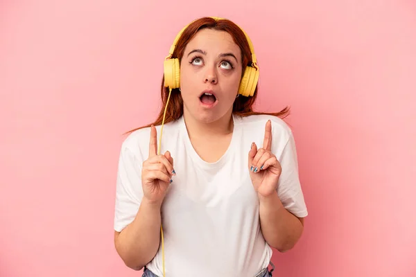 Jonge Kaukasische Vrouw Luisteren Naar Muziek Geïsoleerd Roze Achtergrond Wijzend — Stockfoto