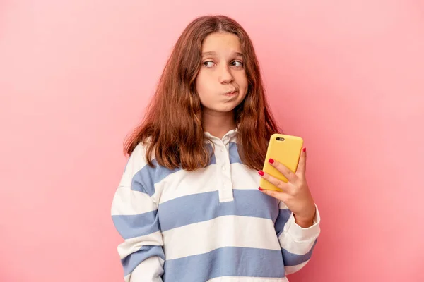 Liten Kaukasiska Flicka Som Håller Mobiltelefon Isolerad Rosa Bakgrund Förvirrad — Stockfoto