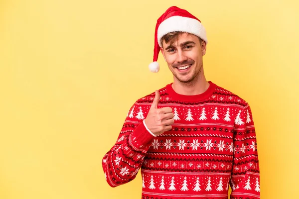 Молодий Кавказький Чоловік Святкує Різдво Ізольовано Жовтому Тлі Посміхаючись Піднімаючи — стокове фото