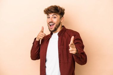 Young arab man isolated on beige background cheerful smiles pointing to front.