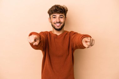 Young arab man isolated on beige background cheerful smiles pointing to front.