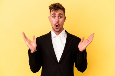 Kafkasyalı genç iş adamı sarı arka planda izole edilmiş, şaşırmış ve şok olmuş..