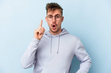 Kafkasyalı genç bir adam mavi arka planda izole edilmiş. Bir fikri, ilham verici bir fikri var..