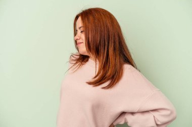 Yeşil arka planda izole edilmiş beyaz bir kadın sırt ağrısı çekiyor..