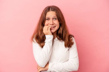 Pembe arka planda izole edilmiş, tırnak yiyen, gergin ve endişeli bir beyaz kız..