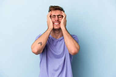 Kafkasyalı genç adam mavi arka planda izole edilmiş sızlanıyor ve ağlıyordu..