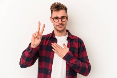 Beyaz arka planda izole edilmiş genç beyaz adam yemin ediyor, elini göğsüne koyuyor..