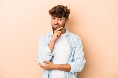 Young arab man isolated on beige background thinking and looking up, being reflective, contemplating, having a fantasy.