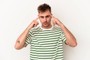 Beyaz arka planda izole edilmiş genç beyaz bir adam bir göreve odaklanmış, işaret parmaklarını işaret ediyor..