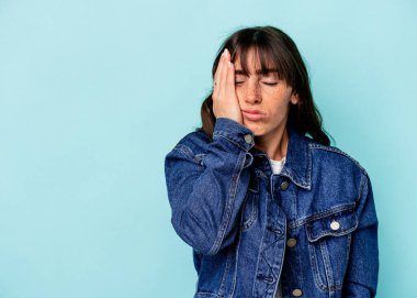 Arjantinli genç bir kadın mavi arka planda izole edilmiş, üzgün ve düşünceli bir şekilde fotokopi odasına bakıyor..