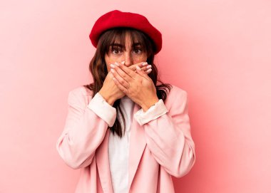 Arjantinli genç bir kadın pembe arka planda izole edilmiş, ağzı kapalı ve elleri endişeli görünüyor..