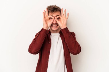 Beyaz arka planda izole genç beyaz adam heyecanlı tamam göz jesti tutmak.