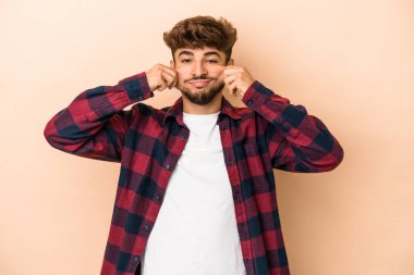 Young arab man isolated on beige background doubting between two options.