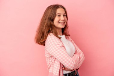 Pembe arka planda izole edilmiş, kendine güveni tam, kararlılıkla kollarını kavuşturan beyaz bir kız..