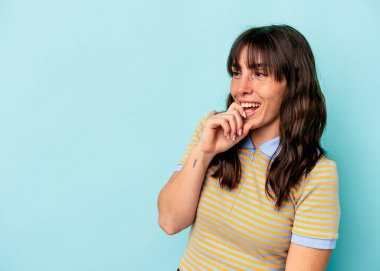 Arjantinli genç bir kadın mavi arka planda izole edilmiş. Rahatlamış bir şekilde bir şeyin fotokopi odasına baktığını düşünüyor..