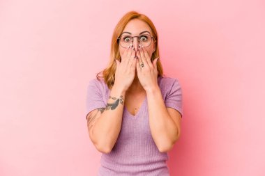 Pembe arka planda izole edilmiş beyaz bir kadın elleriyle ağzını kapatırken şok oldu..