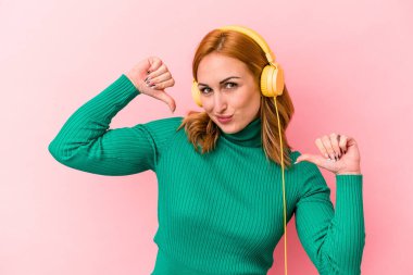 Pembe arka planda izole edilmiş müzik dinleyen genç beyaz kadın gururlu ve kendinden emin hissediyor, örnek olarak..