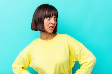 Mavi arka planda soyutlanmış genç melez bir kadın. Gülümsüyor, neşeli ve keyifli görünüyor..