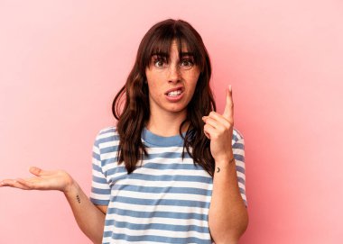 Arjantinli genç bir kadın pembe arka planda izole edilmiş ve elinde bir ürün tutuyor..