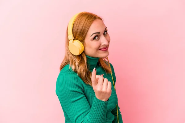 Jonge Kaukasische Vrouw Luisteren Naar Muziek Geïsoleerd Roze Achtergrond Wijzend — Stockfoto