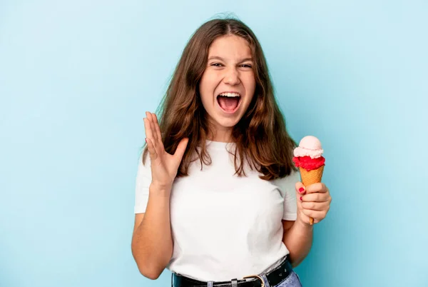 一个白人小女孩吃着一个被蓝色背景隔离的冰淇淋 尖叫着非常愤怒和咄咄逼人 — 图库照片