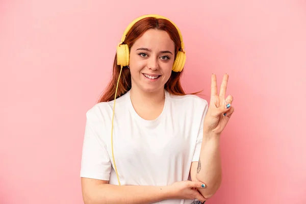 Joven Mujer Caucásica Escuchando Música Aislada Sobre Fondo Rosa Mostrando —  Fotos de Stock