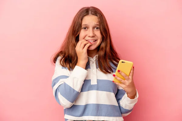 Little Caucasian Girl Holding Mobile Phone Isolated Pink Background Biting — Foto de Stock