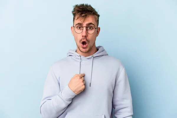 Joven Hombre Caucásico Aislado Sobre Fondo Azul Sorprendido Señalando Con — Foto de Stock