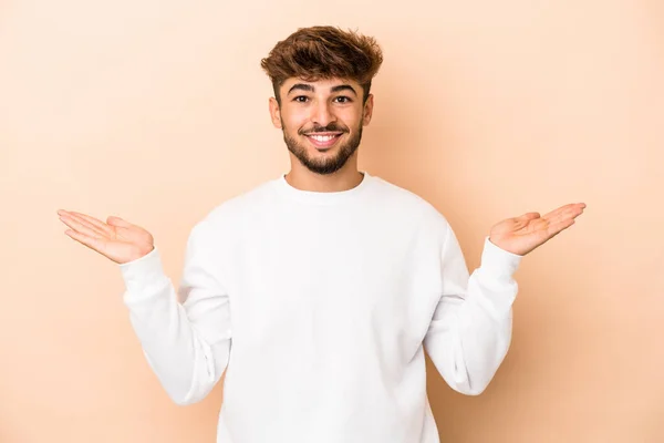 Young Arab Man Isolated Beige Background Makes Scale Arms Feels — Stok fotoğraf